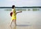 A girl in a dress walks with a guitar barefoot on the water of a lake in nature