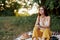 Girl dressed as a hippie eco relaxing in the park, sitting on a blanket in the sunset, relaxed lifestyle