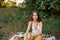 Girl dressed as a hippie eco relaxing in the park, sitting on a blanket in the sunset, relaxed lifestyle