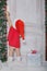 Girl dressed as Santa opens door under snow