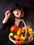 A girl dressed in black on a black background with a basket of vegetables. Halloween Costume