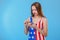 A girl, dressed in bodysuits with an American flag print, unpacks a small gift box. On a blue background.