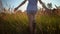 Girl dressed in denim shorts goes through dry golden grass.