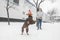 Girl and a dressed dog on a leash play winter in the snow. Photo of a dog jumping over the ball and catching. Woman with a dog