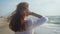 Girl dressed in jeans and white blouse walking along sea shore