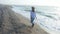 Girl dressed in jeans and white blouse walking along sea shore