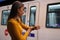 Girl dressed in yellow waiting for the subway car on the underground and watching the time