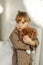 A girl in a dressing gown plays with a knitted hedgehog in the room