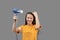 Girl dries hair with a hairdryer on a gray background, having fun