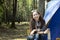 Girl drinking hot water in camping. Beautiful young woman with a tent of outdoor. Asian woman camping and backpack travel sitting