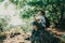 Girl drinking mineral water sitting on stone in forest. Hiker resting with aqua bottle during hike. Thirst quench beverage