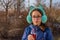 Girl drinks from a bottle in the street. A teenage girl in headphones and glasses