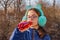 Girl drinks from a bottle in the street. A teenage in headphones and glasses drinks a fruit drink