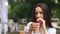 Girl drinks coffee with a straw at an outdoor cafe