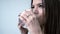 A girl drinks pills from a headache. Behind the light background