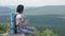 The girl drinks water on peak of the mountain after a long journey to the top.