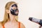 Girl drying peel-off black mask on face