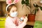 A girl in the ears of a hare makes an Easter bunny in a medical mask out of an egg and plasticine. DIY sitting at home, preparing