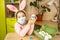 A girl in the ears of a hare makes an Easter bunny in a medical mask out of an egg and plasticine. DIY sitting at home, preparing