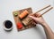 Girl eating an appetizing sushi set with ginger, soy sauce and wasabi on a white background