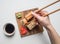 Girl eating an appetizing sushi set with ginger, soy sauce and wasabi on a white background