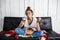 Girl eating chips, drinking soda, watching tv, sitting at sofa.