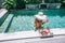 Girl eating fruits in pool on luxury villa in Bali