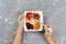 The girl is eating oatmeal with dried fruit. Useful and healthy breakfast on a gray background, top view