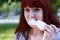 Girl is eating pink candyfloss in bright summer in nature green background