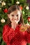 Girl Eating Reindeer Shaped Cookie In Front Of Tre