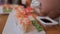 Girl eating sushi at a fast food cafe. Baked sushi rolls with scallop tartare, spicy sauce, cream cheese and mango with