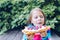 girl eating a waffle with whipped cream, raspberries and blueberries in the garden