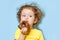 Girl eats, bites a delicious chocolate donut with an appetite and with pleasure, on blue background.