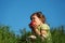 Girl eats red apple in grass against blue sky
