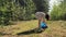 A girl eco activist collects garbage in the forest, in the summer. A volunteer collects plastic bottles in the park, in nature.