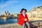 Girl on embankment near Notre Dame de Paris with Christmas gift