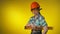 Girl engineer builder in an orange safety helmet holds a level ruler in hands