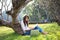 Girl enjoy reading a book under the tree, laying on grass of park