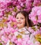 Girl enjoying floral aroma. Kid on pink flowers sakura tree background. Child enjoy life without allergy. Sniffing