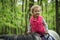 Girl enjoying horseback riding in the woods, young pretty girl with blond curly hair on a horse with backlit leaves