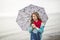 Girl enjoying the rain and having fun outside on the beach a gray rainy