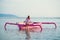 The girl enjoys the warm ocean sitting on a pink boat and lowering her legs into the water