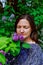 Girl enjoys wonderful smell of lilac. flowers in hands is standing near blooming lilac tree