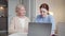 A girl enters an elderly woman room to explain to her how to use a laptop.