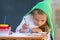 Girl enthusiastically paints watercolors sitting at a table in the yard