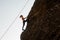 Girl equipped with a rope climbing on the sloping rock
