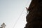 Girl equipped with a rope climbing on the sloping rock and looking down