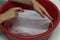 The girl erases a children`s white T-shirt in a red basin from stains, cleans from stain remover, close-up, hands white background