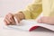 Girl erasing mistake in her notebook at white desk indoors, closeup