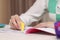 Girl erasing mistake in her notebook at white desk indoors, closeup